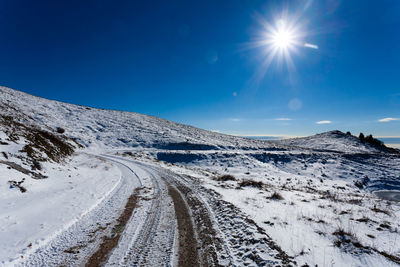 Scenic view of snow covered mountain against blue sky