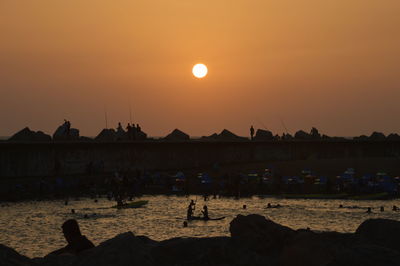 Silhouette of tourists on boats in sea