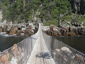 Panoramic view of footbridge over rocks in forest