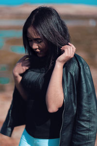 Young woman wearing leather jacket standing outdoors