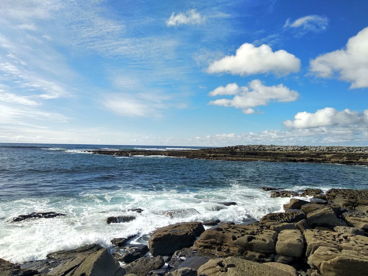 SCENIC VIEW OF ROCKY BEACH AGAINST SKY