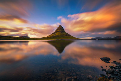 Scenic view of lake against dramatic sky during sunset