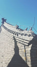 Shadow of person on wall against clear sky