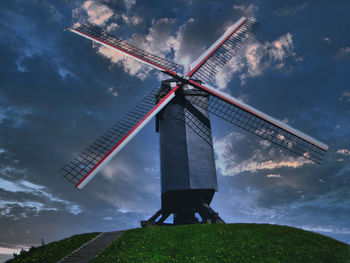 Low angle view of traditional windmill on field against sky