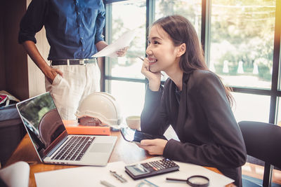 Young woman using mobile phone while sitting on table