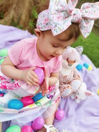 Full length of cute girl holding easter eggs while sitting outdoors