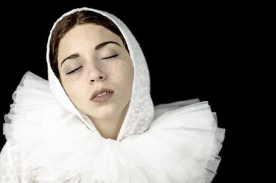 Close-up of young woman against black background