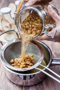 Close-up of person straining liquid into pot