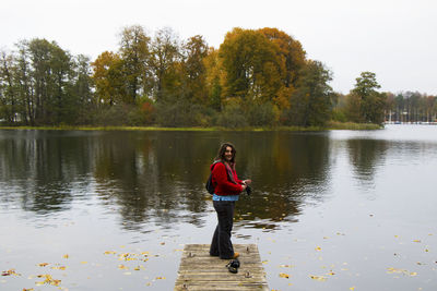 Full length portrait of woman standing by lake