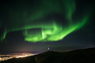 Man standing on mountain against aurora borealis