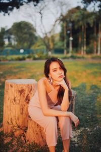 Portrait of young woman sitting on tree stump