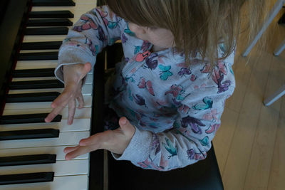 High angle view of girl playing piano at home