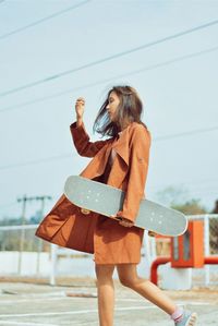 Woman holding skateboard while standing on road