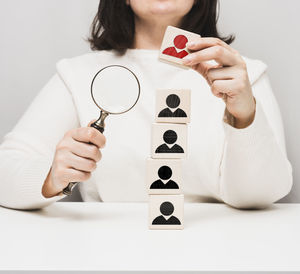 Woman holding a magnifying glass and wooden cubes on a white table. personnel recruitment 