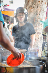 Low angle view of woman wearing helmet looking at food while standing on street