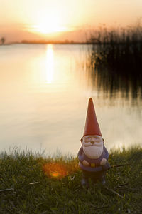 Scenic view of lake against sky during sunset with garden gnome 