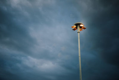 Low angle view of bird perching on pole against sky