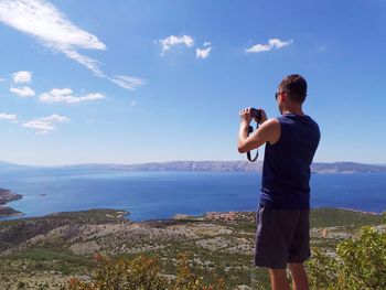 Full length of man photographing sea against sky