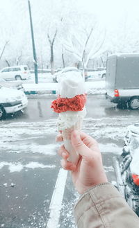 Close-up of hand holding ice cream cone on street