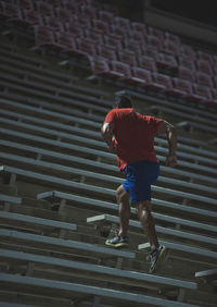 Low angle view of young man moving up on seats in stadium