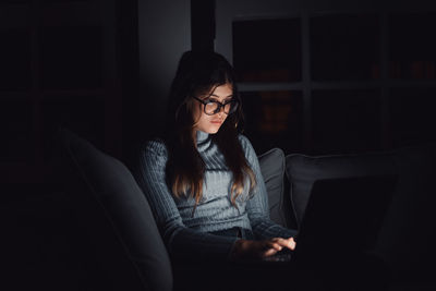 Portrait of young woman sitting on sofa at home