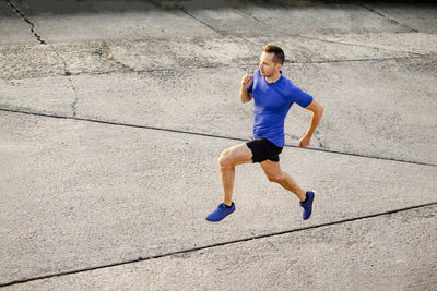 Man athlete runner running on concrete road