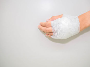 Cropped image of woman hand wrapped with bandage against white background