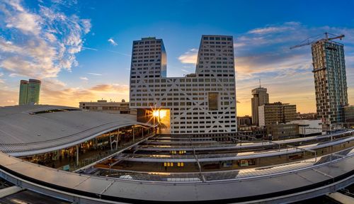 Modern buildings in city against sky during sunset