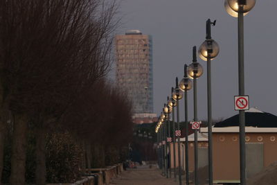 Street lights on road against buildings at dusk