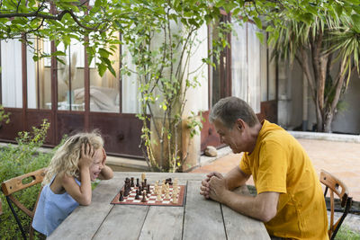 Granddaughter and grandfather enjoying chess in garden