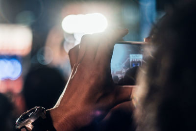 Cropped image of man photographing with mobile phone at night