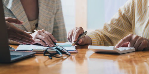 Midsection of woman using laptop on table