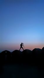 Silhouette man photographing against clear sky during sunset