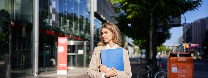 Portrait of young woman standing in city