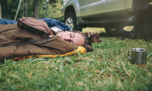 Woman napping in sleeping bags on grassy field