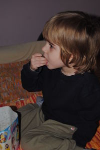 High angle view of boy eating food while sitting on bed at home