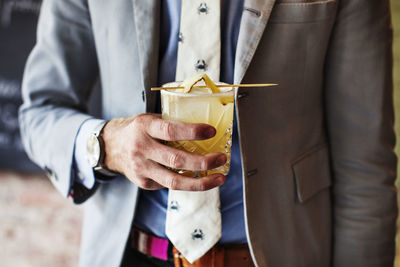 Midsection of man holding drink while standing in restaurant