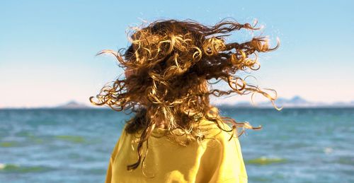 Woman shaking head while standing against sea