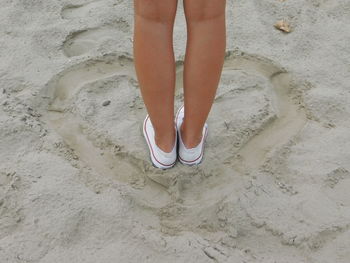 Low section of woman standing on sand at beach