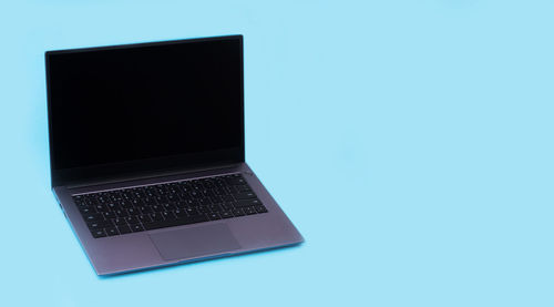 Close-up of laptop on table against blue background