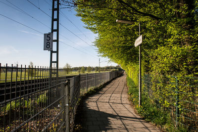 Footpath amidst plants and fence against sky. unterhaching. germany