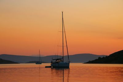 Sailboat sailing on sea against orange sky