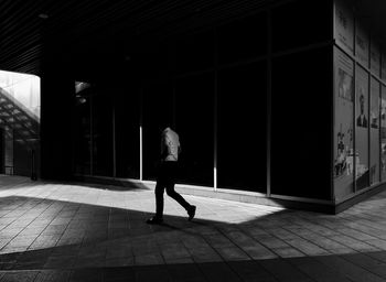 Rear view of woman walking on footpath against building