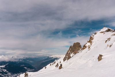 Scenic view of snow covered mountains against cloudy sky