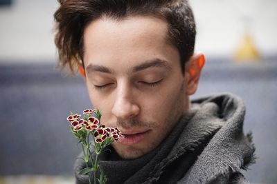 Close-up of young man with eyes closed smelling flowers
