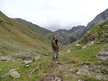 Rear view of man with backpack walking on land against sky