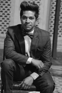 Portrait of young man wearing suit while sitting outdoors