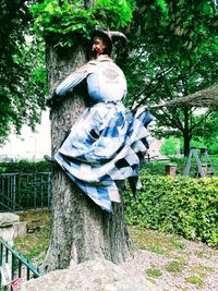 Young man standing by tree against plants