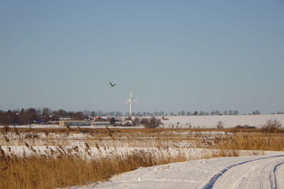 Street amidst field against clear sky during winter