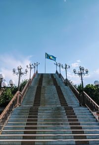 Low angle view of staircase with flag against sky